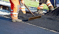 People in orange work gear paving a road